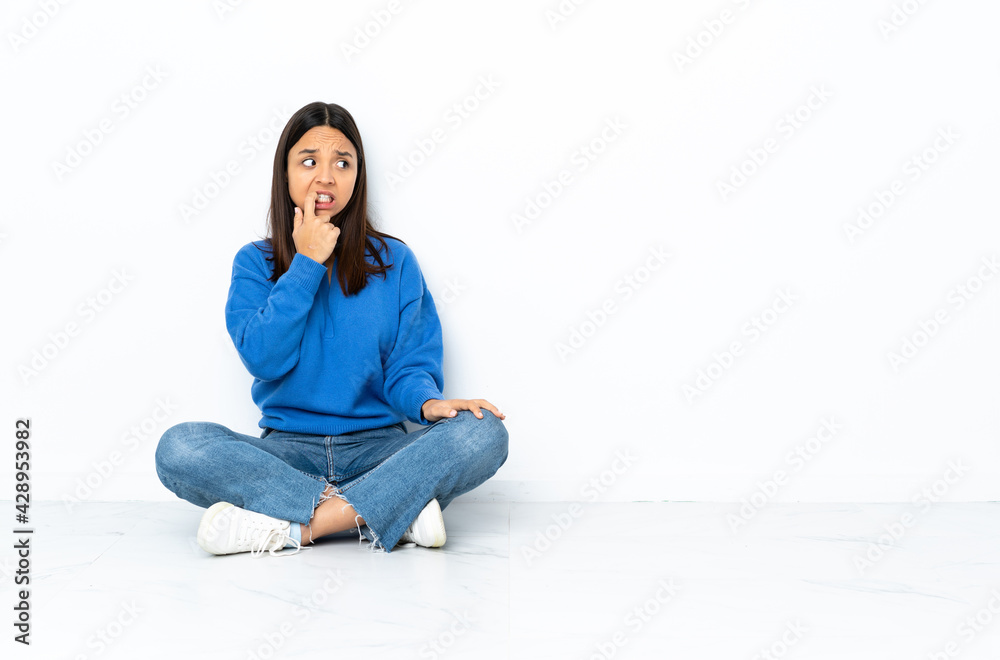 Young mixed race woman sitting on the floor isolated on white background nervous and scared Young mixed race woman sitting on the floor isolated on white background nervous and scared