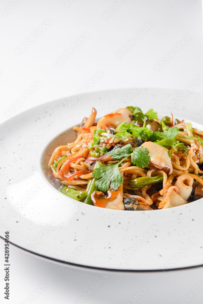 Sea food wok stir fry served in a white plate. Clams and shrimps wok isolated on white.