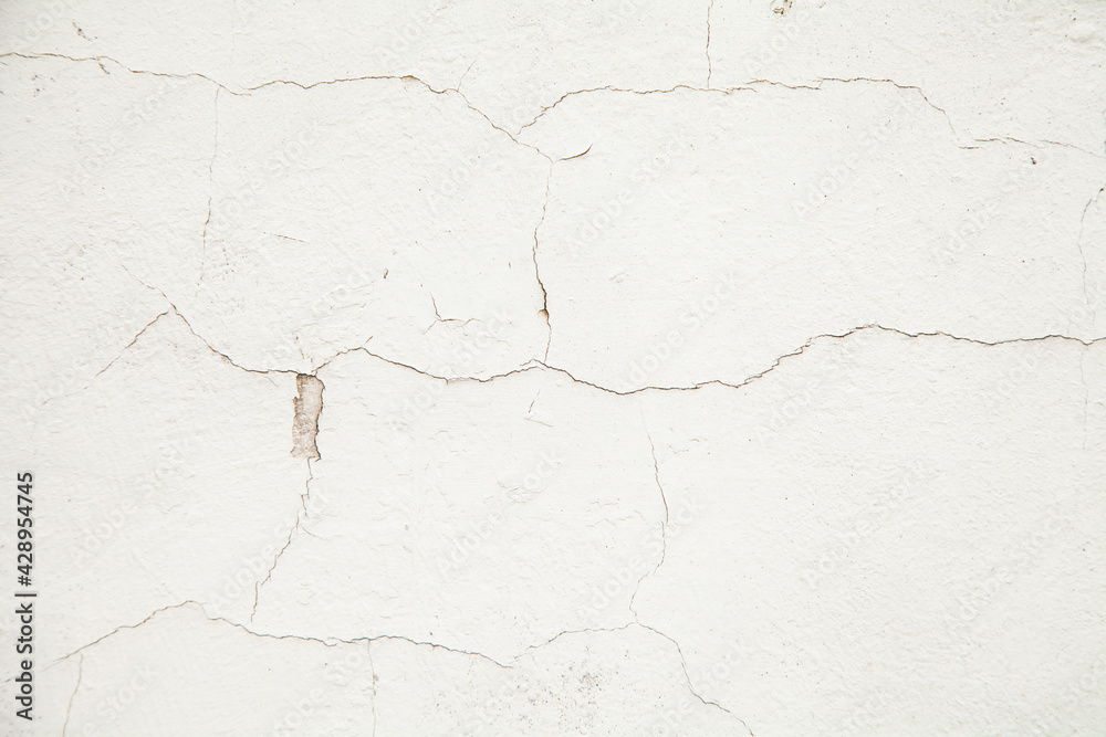 White wall with cracks. Cracks texture on a white abstract background. Cracked plaster on the wall