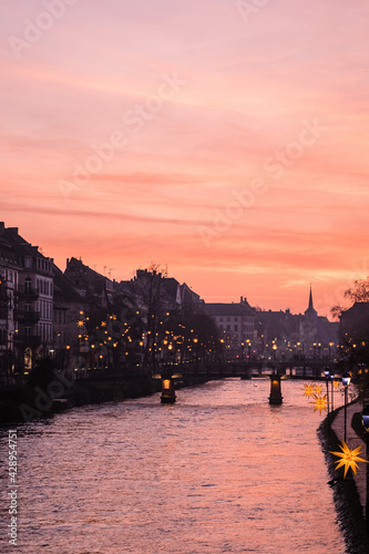 Beautiful on river Rhein in Strasbourg during sunset. City in the dusk, purple sky. City in France. Flower garland at the river.