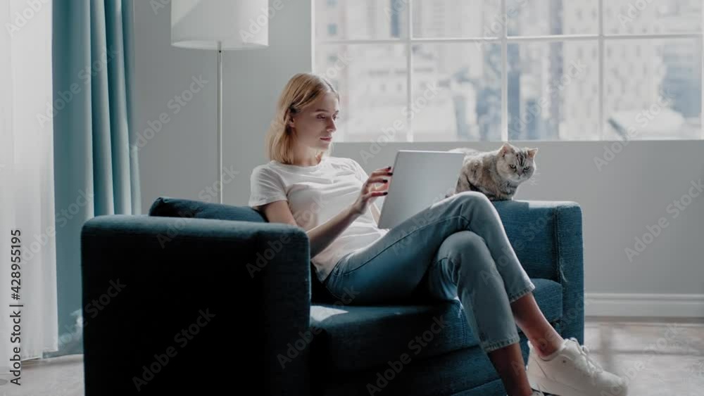 Tranquil woman uses tablet near purebred cat on couch