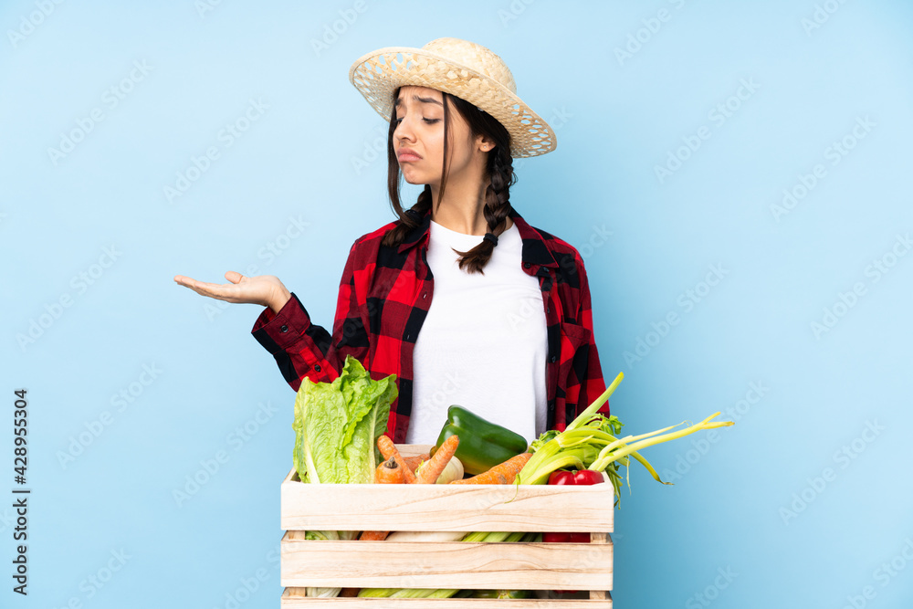 Young farmer Woman holding fresh vegetables in a wooden basket holding copyspace with doubts