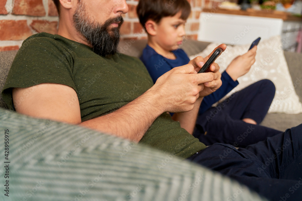 Close up side view of father and son using mobile phone Close up side view of father and son using mobile phone