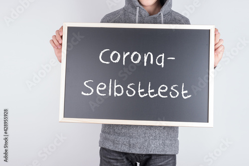 Schüler mit einer Tafel Corona Selbsttest photo