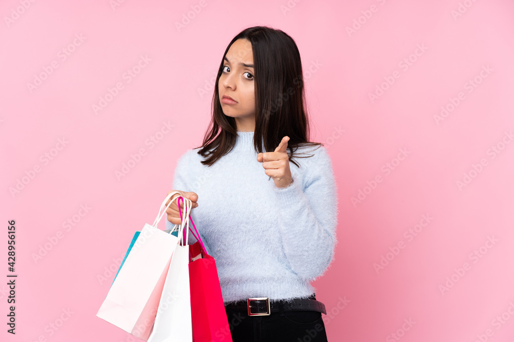 Young woman with shopping bag over isolated pink background frustrated and pointing to the front Young woman with shopping bag over isolated pink background frustrated and pointing to the front