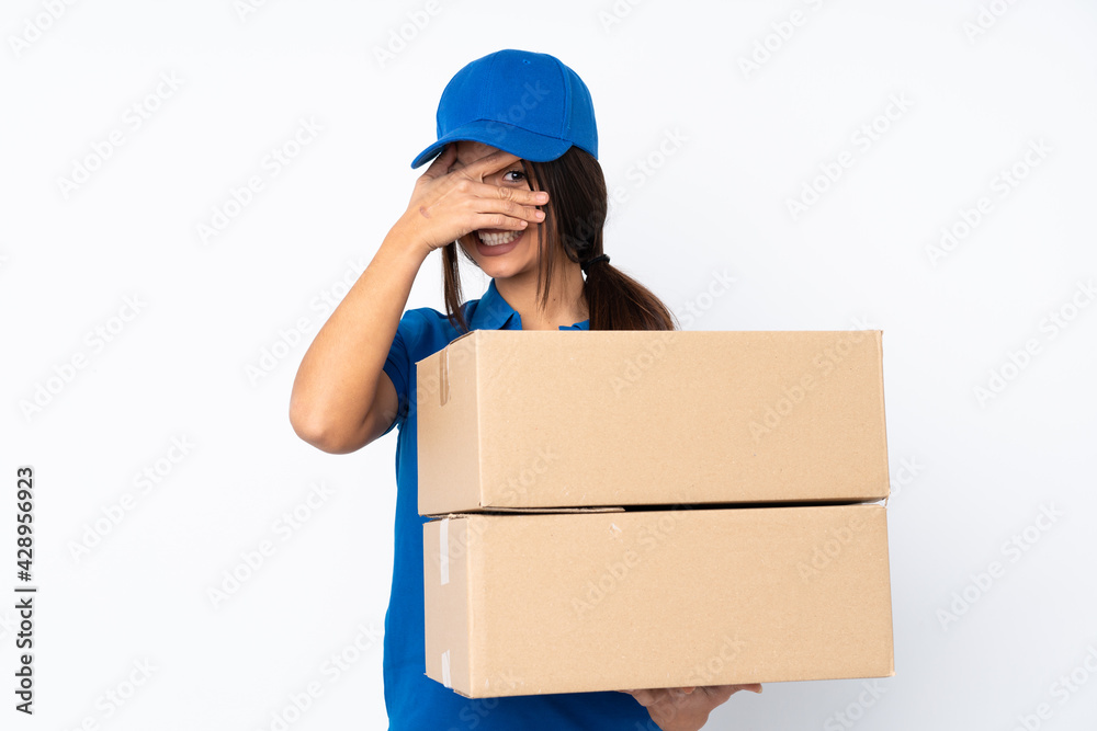 Young delivery brunette girl over isolated white background covering eyes by hands and smiling Young delivery brunette girl over isolated white background covering eyes by hands and smiling