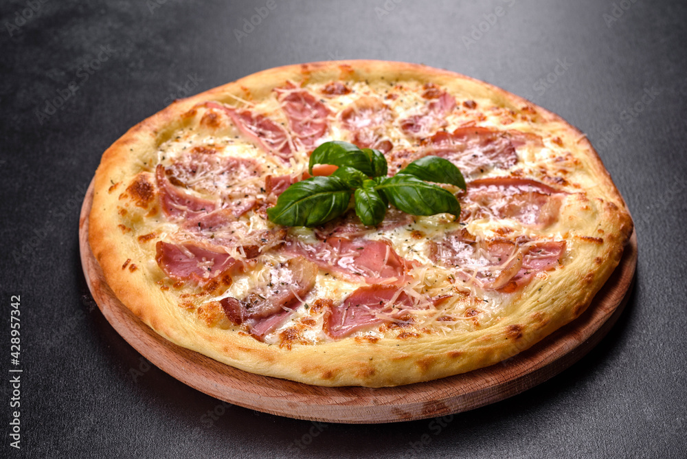 Delicious fresh crispy pizza from the oven with ham, cheese and basil