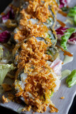 Delicious vegetarian tempura sushi rolls, served on a white plate. vertical picture