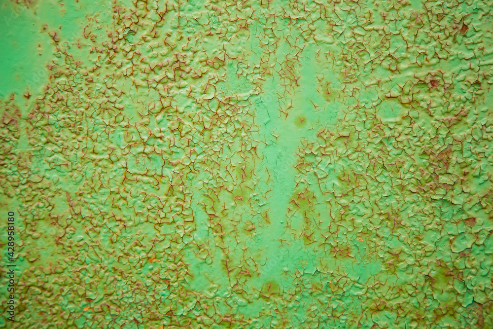 Green metal texture with patches of rust steel on its surface, taken outdoor. The pattern of an old painted metal surface. Rusty metal, peeling paint, green tones, bright colors.