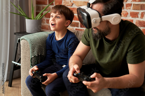 Father wearing VR glasses playing with son at home