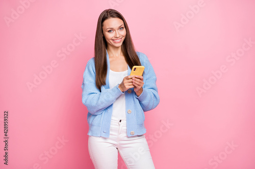 Photo of happy cute young lady good mood hold smartphone blogger isolated on pastel pink color background