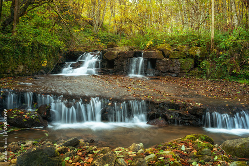 Waterfall flowing through rocks in a deep forest, autumn landscape
