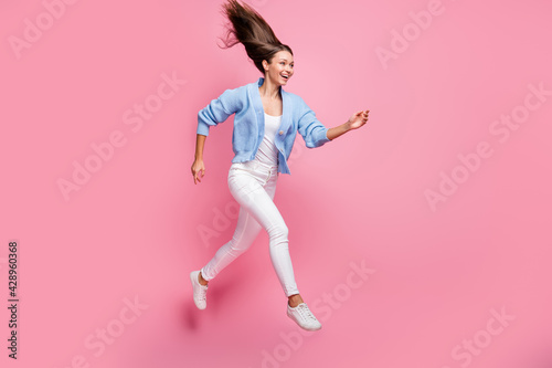 Full body profile side photo of excited girl look run copyspace jump air sale fly hair isolated on pastel pink color background