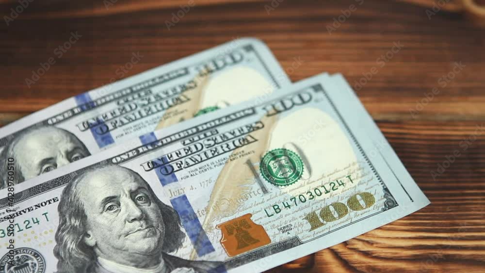 Women's hands count money: they shift dollars on a wooden table, flip through bills. One hundred dollars. A stack of $ 100 bills in close-up. Finance, economy, financial planning, economics, savings. Women's hands count money: they shift dollars on a wooden table, flip through bills. One hundred dollars. A stack of $ 100 bills in close-up. Finance, economy, financial planning, economics, savings.