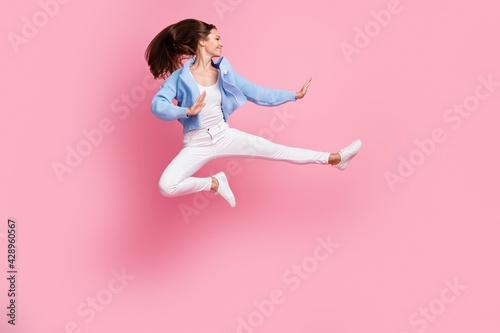 Full length profile side photo of young active woman jump up air ninja pose kick isolated on pastel pink color background