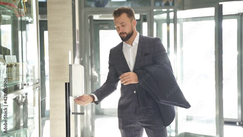 Man in business suit performs hand dysingfection in lobby of the hotel. Man in business suit performs hand dysingfection in lobby of the hotel.