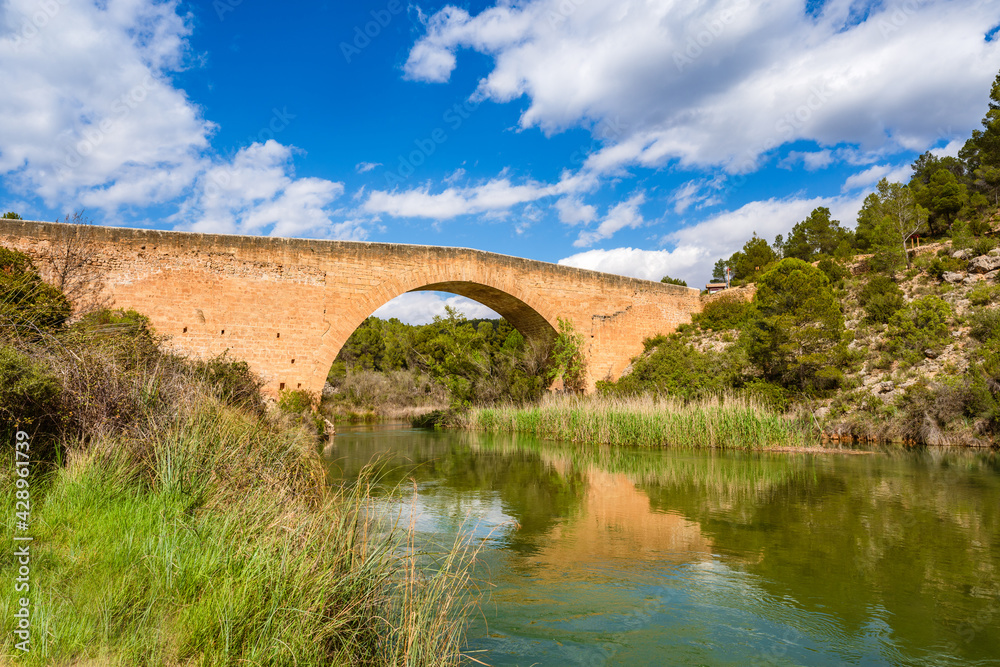 Antique one arch stone bridge over a river the Hoces del Rio Cabriel Natural Park between Valencia and Cuenca in Spain. Protected Area. 