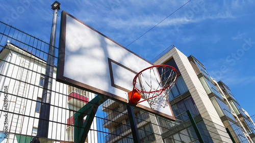 backyard playground - basketball hoop on a backboard against a backdrop of residential buildings and blue sky