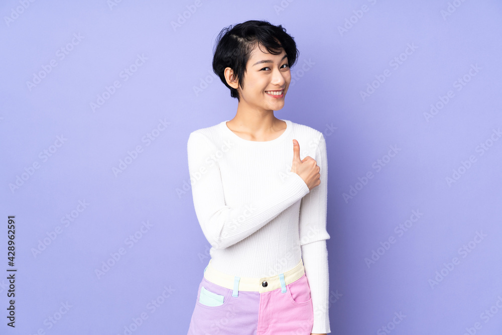 Young Vietnamese woman with short hair over isolated purple background giving a thumbs up gesture Young Vietnamese woman with short hair over isolated purple background giving a thumbs up gesture