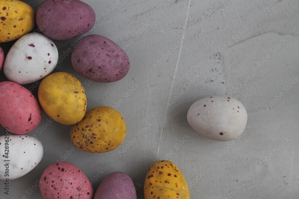 Multi-colored Easter eggs. Colored chocolate eggs to decorate the cake. Easter decoration. Quail colored eggs. Festive Easter food. Colored eggs on a gray concrete background. Easter eggs horizontally