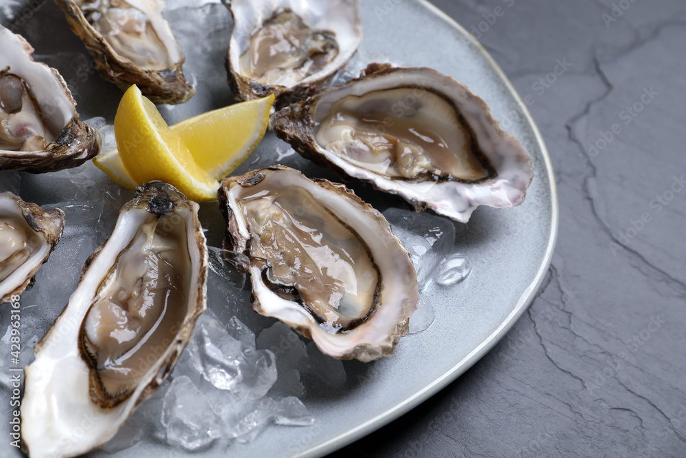 Delicious fresh oysters with lemon slices served on table, closeup Delicious fresh oysters with lemon slices served on table, closeup