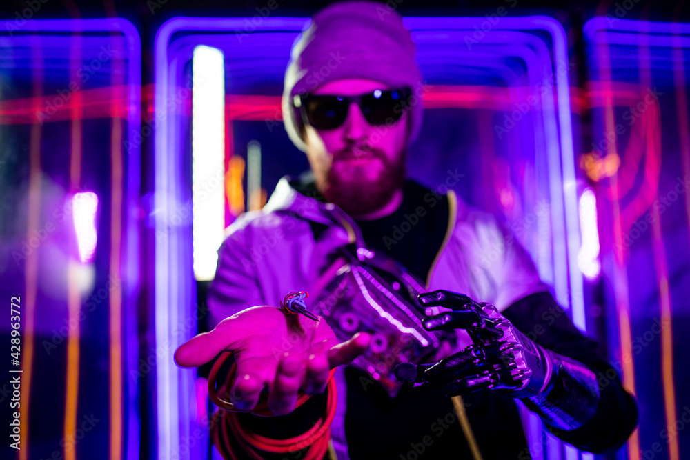 handsome young man with metal bionics prosthetic arm wrapped on wire in neon background space handsome young man with metal bionics prosthetic arm wrapped on wire in neon background space
