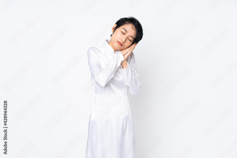 Young Vietnamese woman with short hair wearing a traditional dress over isolated white background making sleep gesture in dorable expression Young Vietnamese woman with short hair wearing a traditional dress over isolated white background making sleep gesture in dorable expression