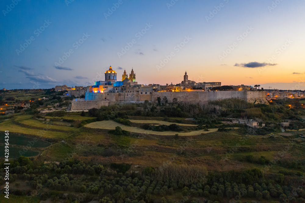 Mdina city - old capital of Malta. Evening, nature landscape, sunset sky. Colourful lights in the city