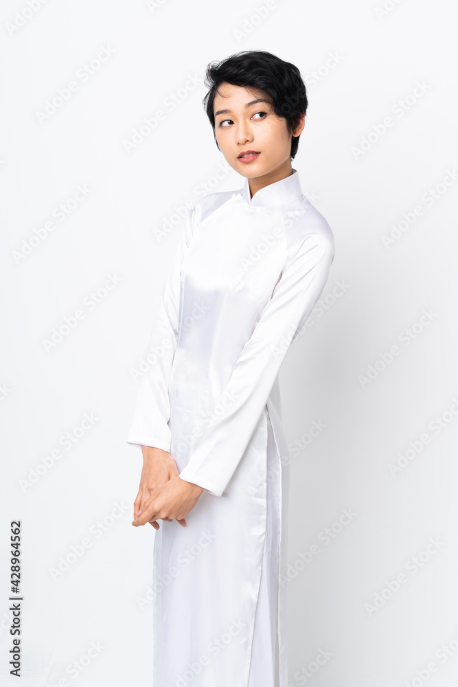 Young Vietnamese woman with short hair wearing a traditional dress over isolated white background Young Vietnamese woman with short hair wearing a traditional dress over isolated white background