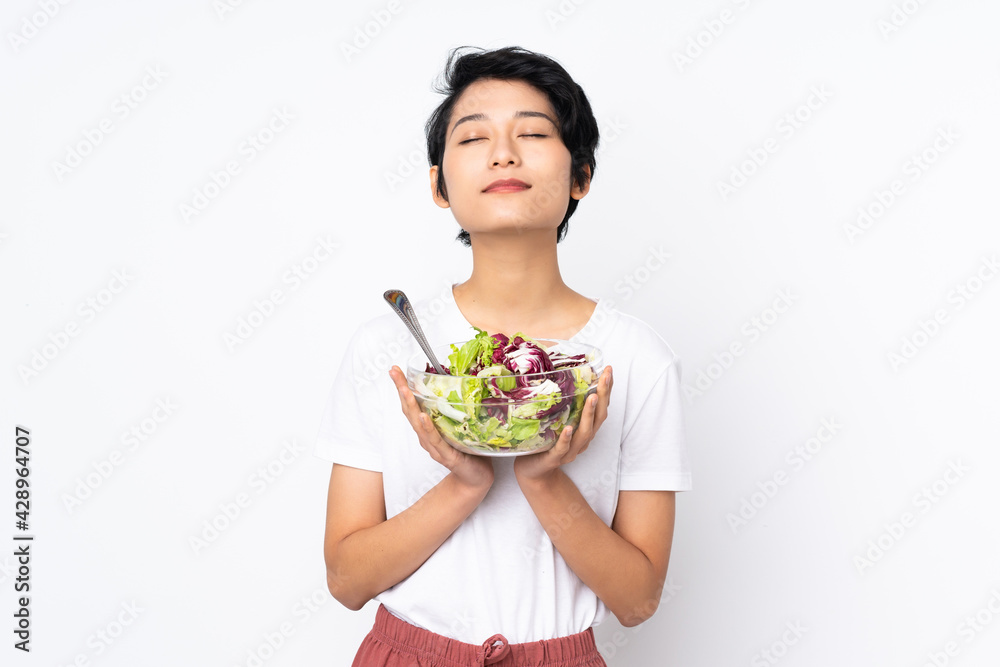 Young Vietnamese woman with short hair holding a salad over isolated background Young Vietnamese woman with short hair holding a salad over isolated background