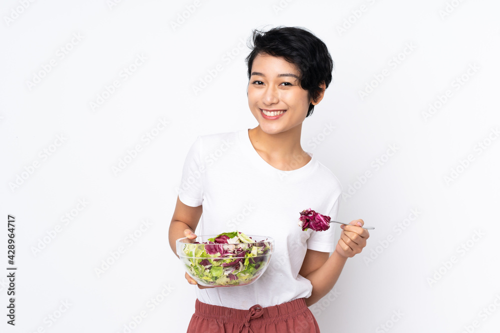 Young Vietnamese woman with short hair holding a salad over isolated background Young Vietnamese woman with short hair holding a salad over isolated background