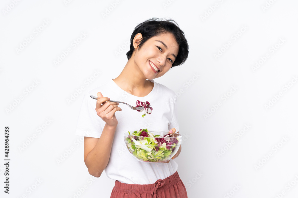 Young Vietnamese woman with short hair holding a salad over isolated background Young Vietnamese woman with short hair holding a salad over isolated background