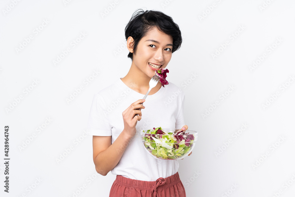 Young Vietnamese woman with short hair holding a salad over isolated background