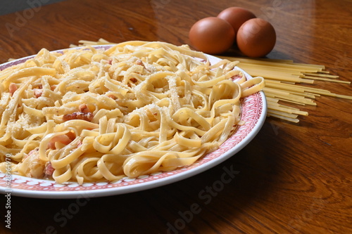 delicious plate of carbonara style spaghetti with grated cheese. plate of fresh pasta with ingredients. noodles and eggs with pasta carbonara.