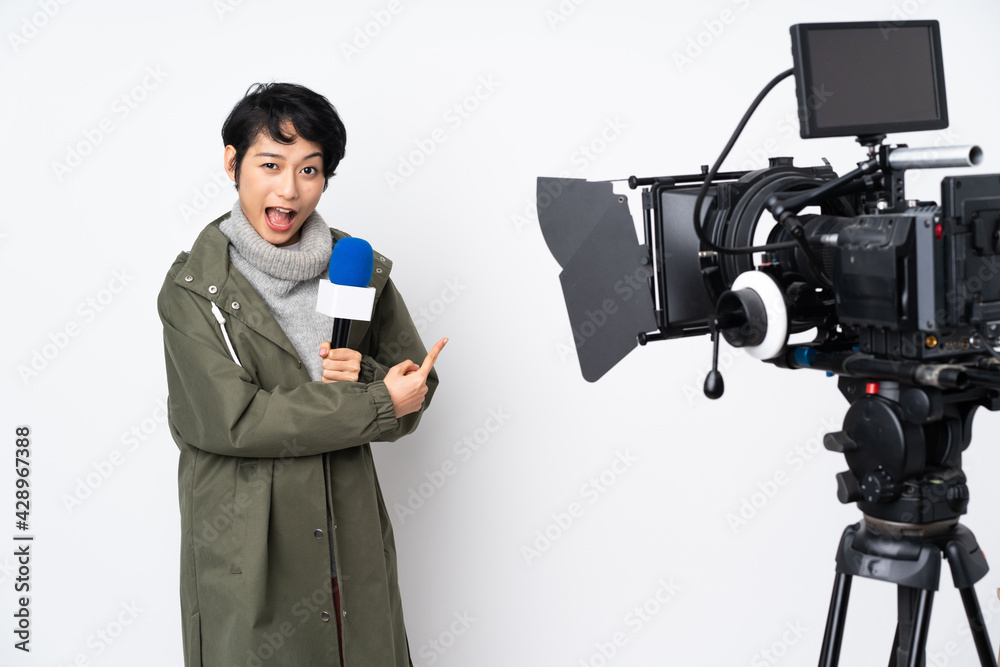 Reporter Vietnamese woman holding a microphone and reporting news surprised and pointing side