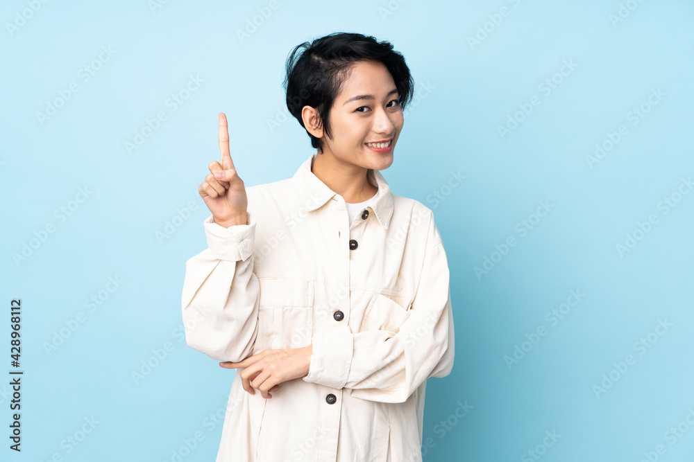 Young Vietnamese woman with short hair over isolated background happy and pointing up Young Vietnamese woman with short hair over isolated background happy and pointing up
