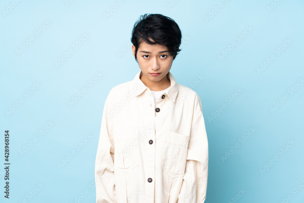 Young Vietnamese woman with short hair over isolated background with sad expression Young Vietnamese woman with short hair over isolated background with sad expression