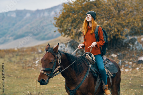 woman hiker with a backpack rides a horse in the mountains nature travel