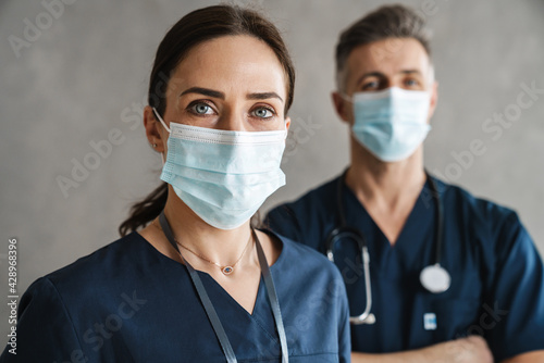 Two confident doctors in medical masks standing