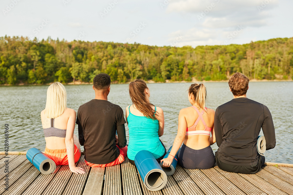 Friends sit by the lake after a fitness class Friends sit by the lake after a fitness class