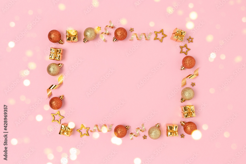 Gold glittering frame made of Christmas toys and confetti on a pink background. Glowing festive concept with place for text.