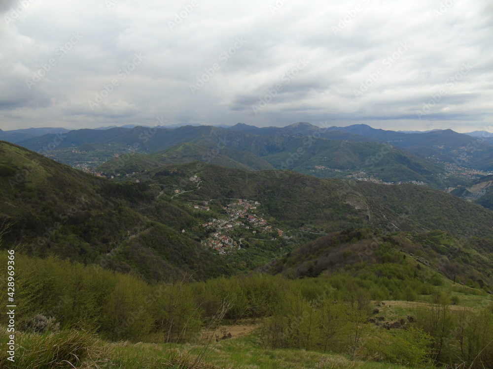 Genova, Italy - April 14, 2021: Panoramic view to the mountains over the city of Genova, and small part of the port. Grey sky in the background.