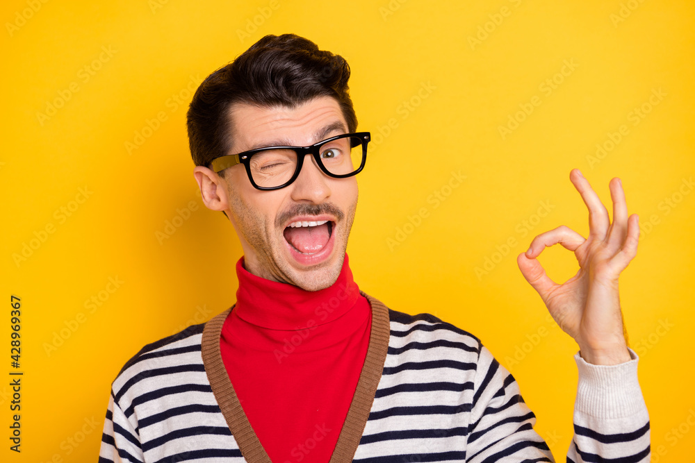 Naklejka premium Photo of young man happy smile blink eye show okey sign deal done cool alright advert advise isolated over yellow color background