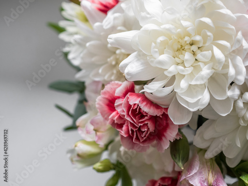 Bouquet close-up. Bouquet of white chrysanthemums, red carnations and eucalyptus leaves. On the windowsill by the window © Anastasiia