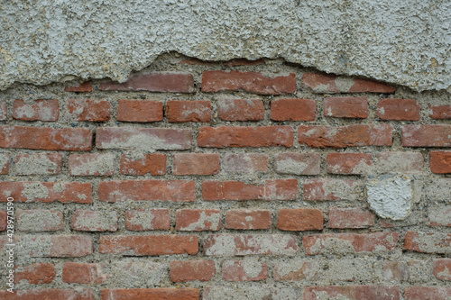 Eine schmutzige alte Mauer   Ziegelmauer aus roten Ziegelsteinen Textur   Hintergrund   Deko   oben h  ngen die Reste vom Putz  unten ist der Putz abgebrochen
