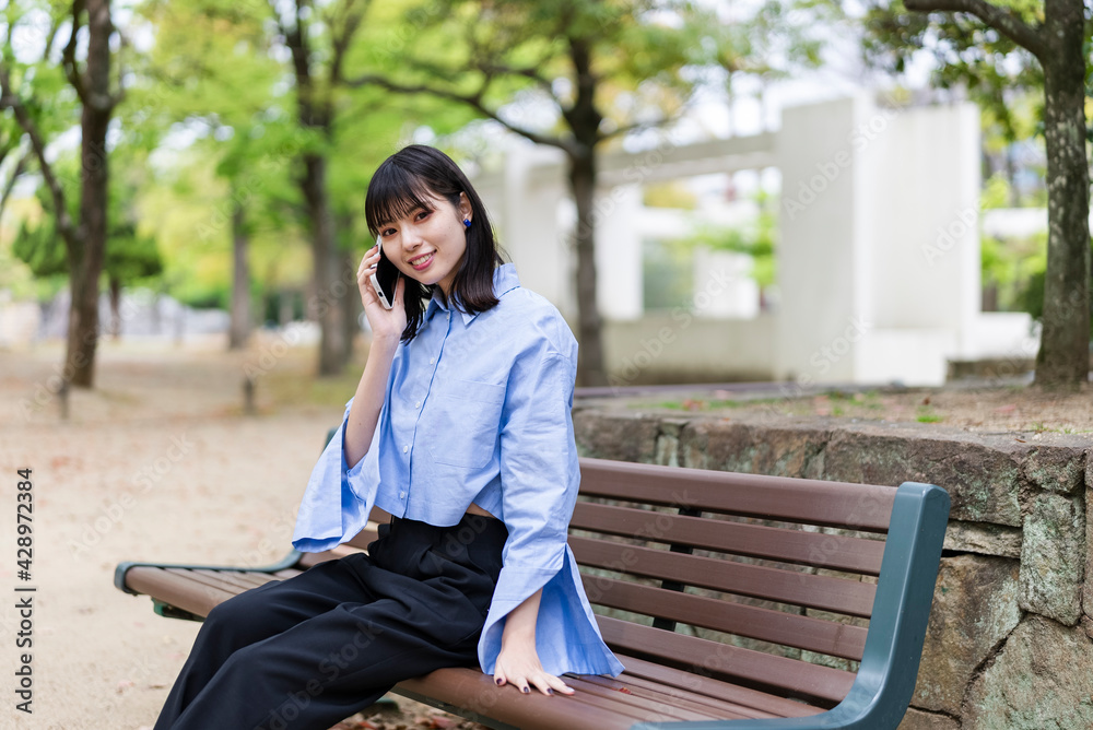 公園で携帯電話を使う女性 公園で携帯電話を使う女性