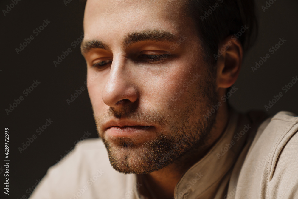 Obraz premium Close up of a sad upset brunette man looking down