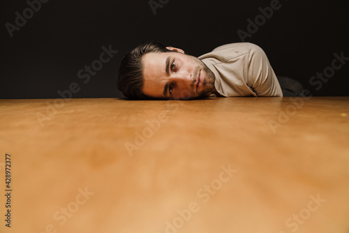 Upset sad man laying his head on a table indoors