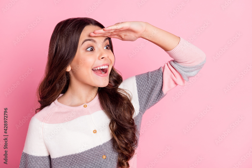 Fototapeta premium Photo of excited happy little girl look forward empty space smile isolated on pastel pink color background