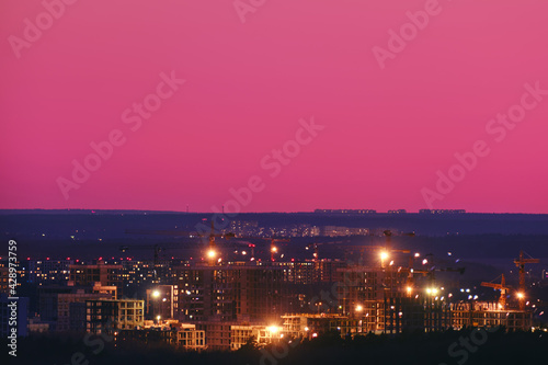 Pink sky over under construction city buildings with tower cranes